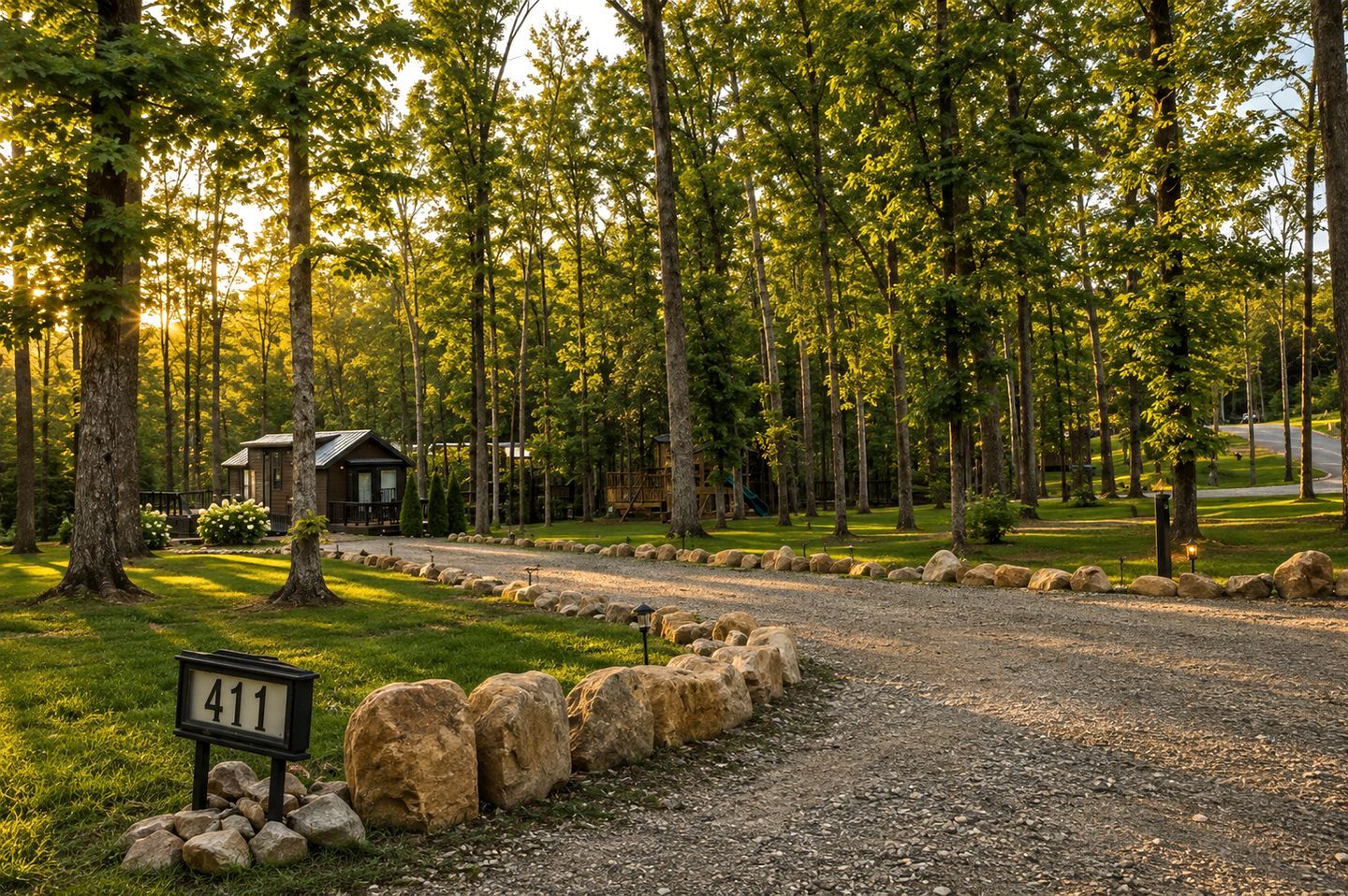 A gravel driveway leading to a cabin with a sign reading '411' in a forested area.