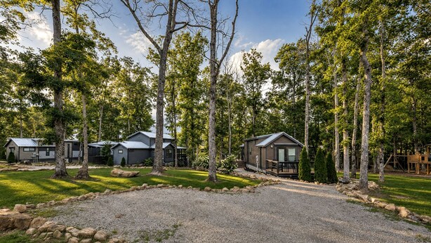 A campground with multiple cabins, a gravel driveway, and surrounding trees. - Tranquil Cabin with Fire Pit and Panoramic Lake Views in Tennessee (Tracy City)