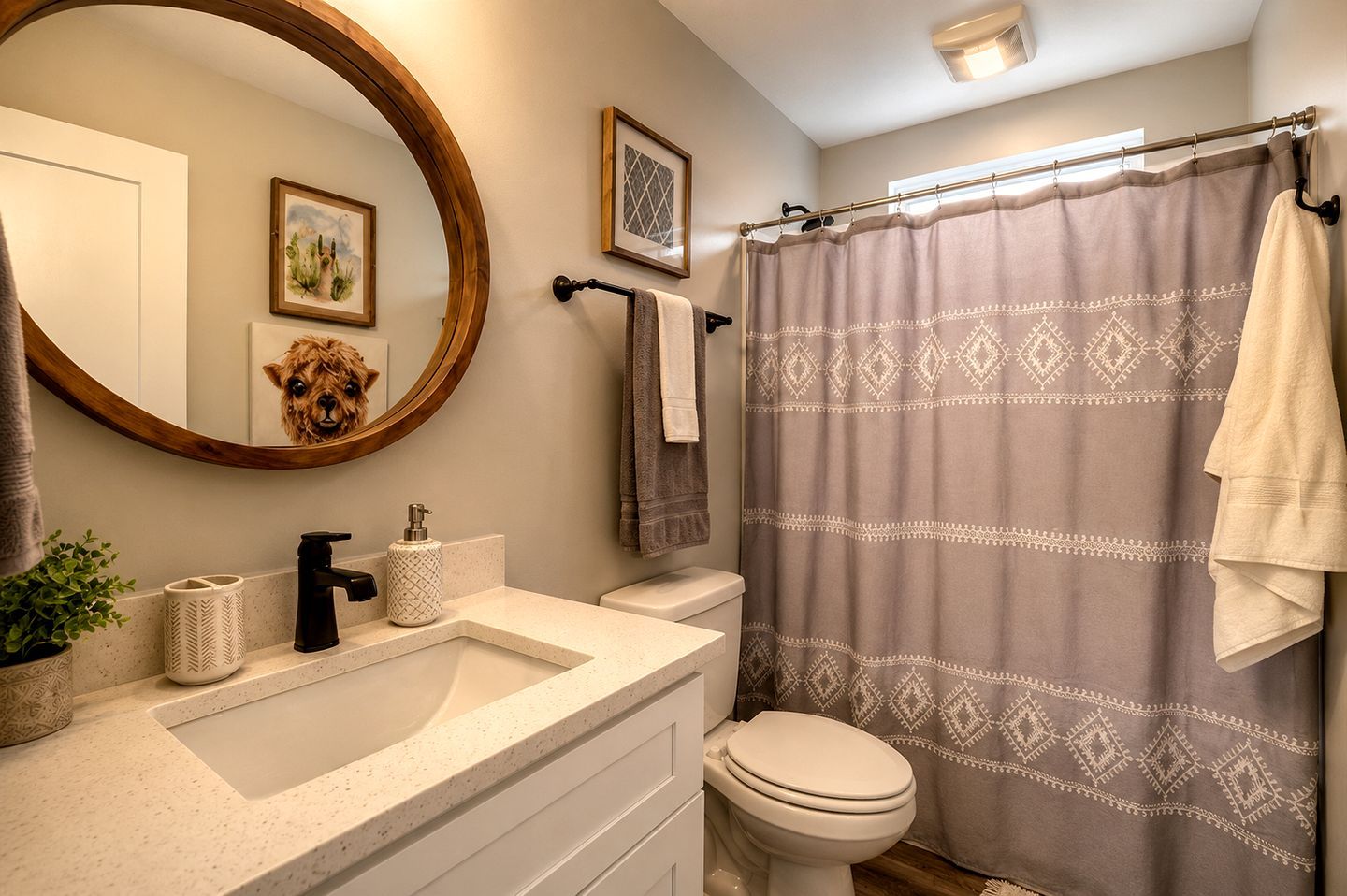 A bathroom with a round mirror, a sink with a soap dispenser, a toilet, and a shower curtain with a geometric pattern.