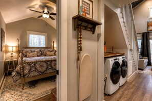 A bedroom with a bed, a ceiling fan, a window, and a nightstand with a lamp.