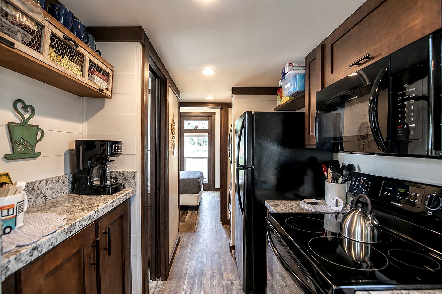 Una cocina equipada con refrigerador, estufa, microondas y cafetera.
