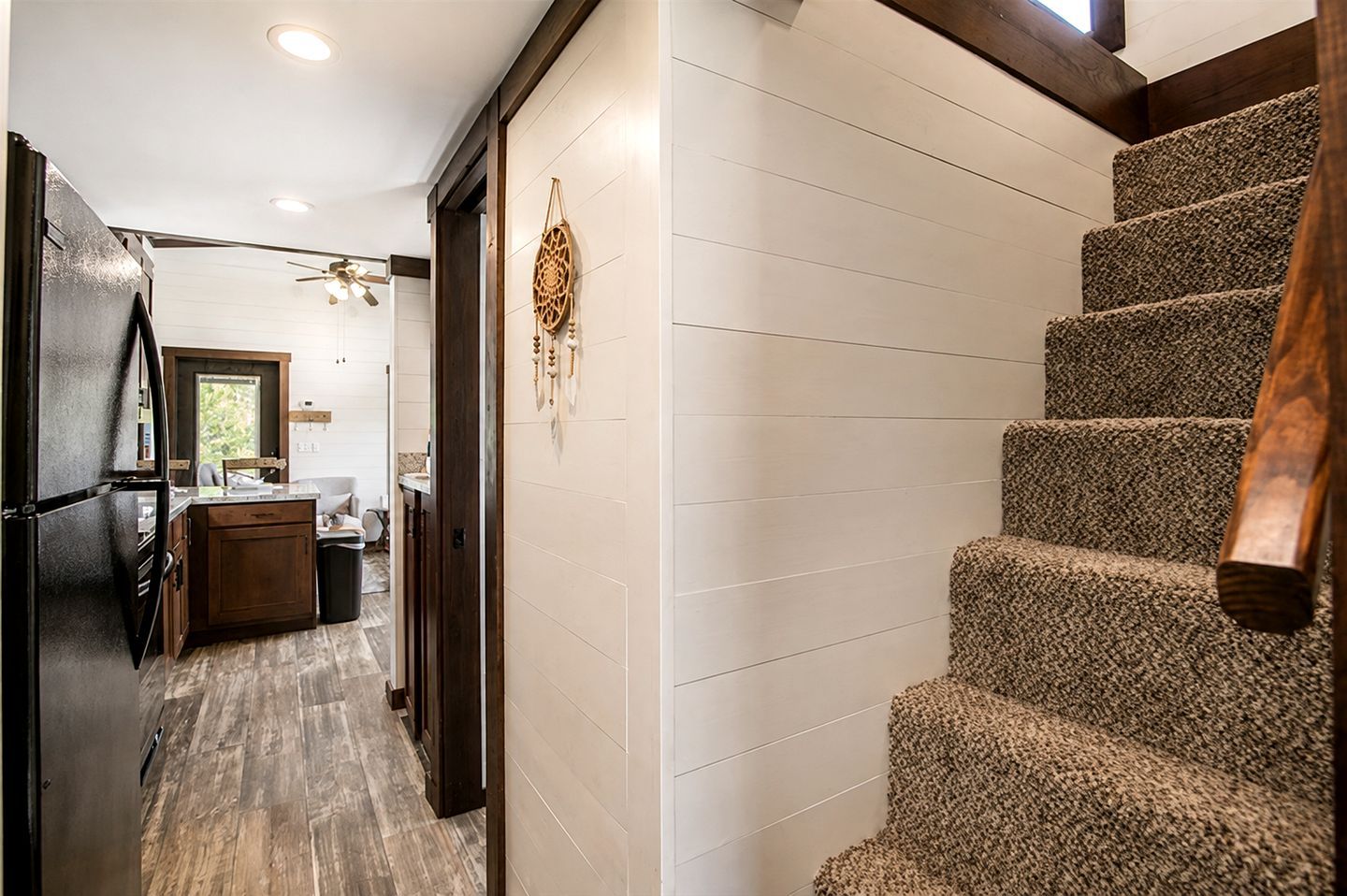 Una escalera de madera con barandilla, que conduce a un rellano con un tapiz decorativo.