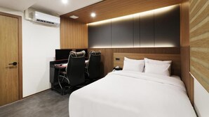A hotel room with a bed, a desk with two chairs, and a built-in wardrobe. - Hotel Oneul (Incheon)
