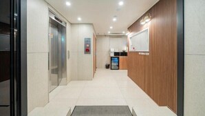 A modern hotel lobby with a reception desk, a trash bin, and an elevator. - Hotel Oneul (Incheon)