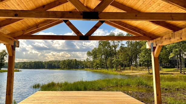 Una terraza de madera con vistas a un lago y un bosque.
