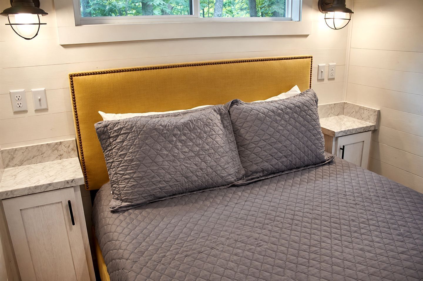 A bed with a headboard, two pillows, and a quilted bedspread.