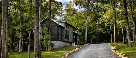 A cabin with a gravel driveway surrounded by trees.