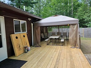 A wooden deck with a covered picnic area, a wooden playhouse, and a wooden fence. - Beautiful Cottage Nestled Amidst Trees in Wellston, Michigan (Wellston)