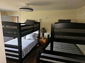 A room with bunk beds, a lamp, and a door. - Beautiful Cottage Nestled Amidst Trees in Wellston, Michigan (Wellston)