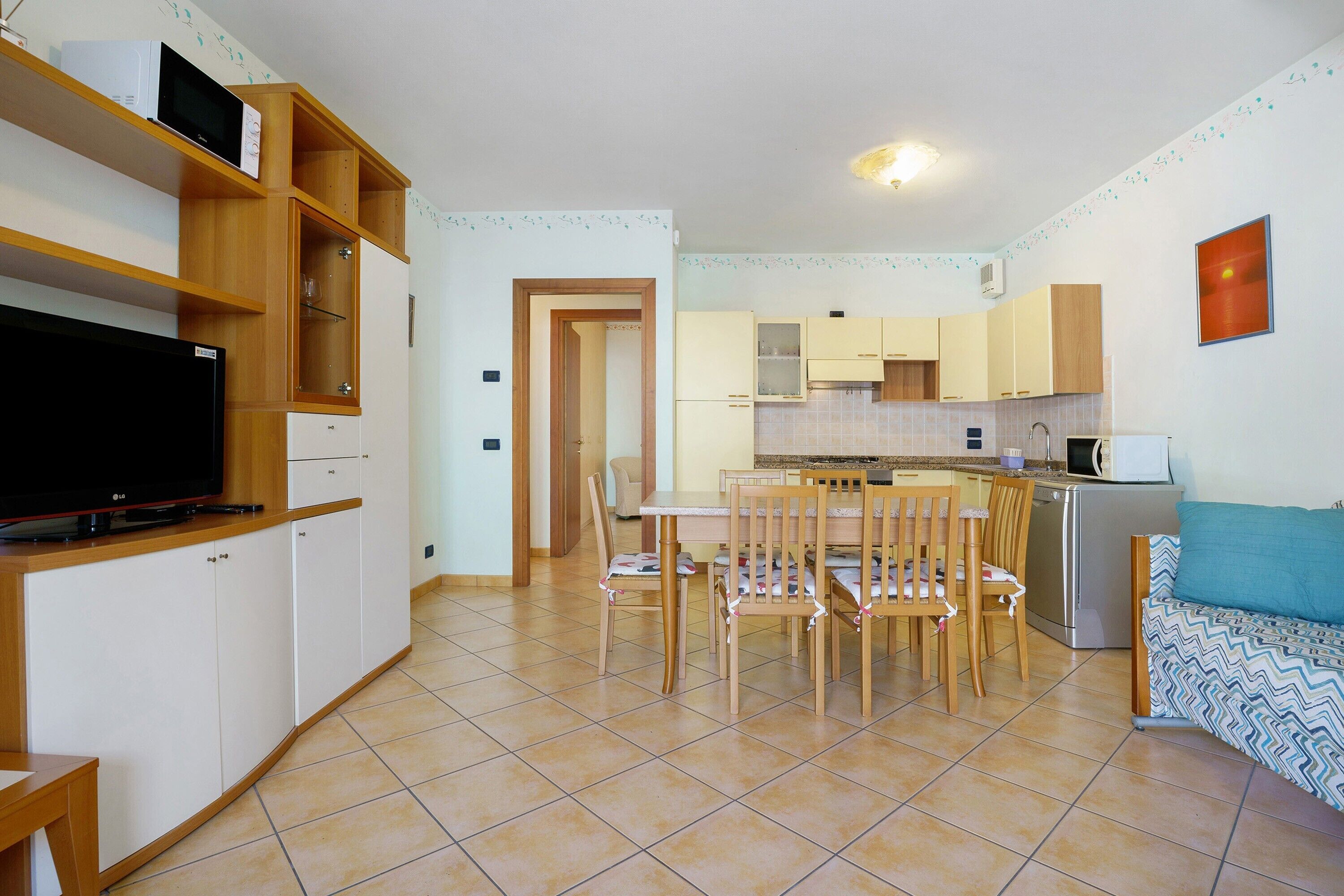A compact kitchen with a dining area, a TV, and a sofa.