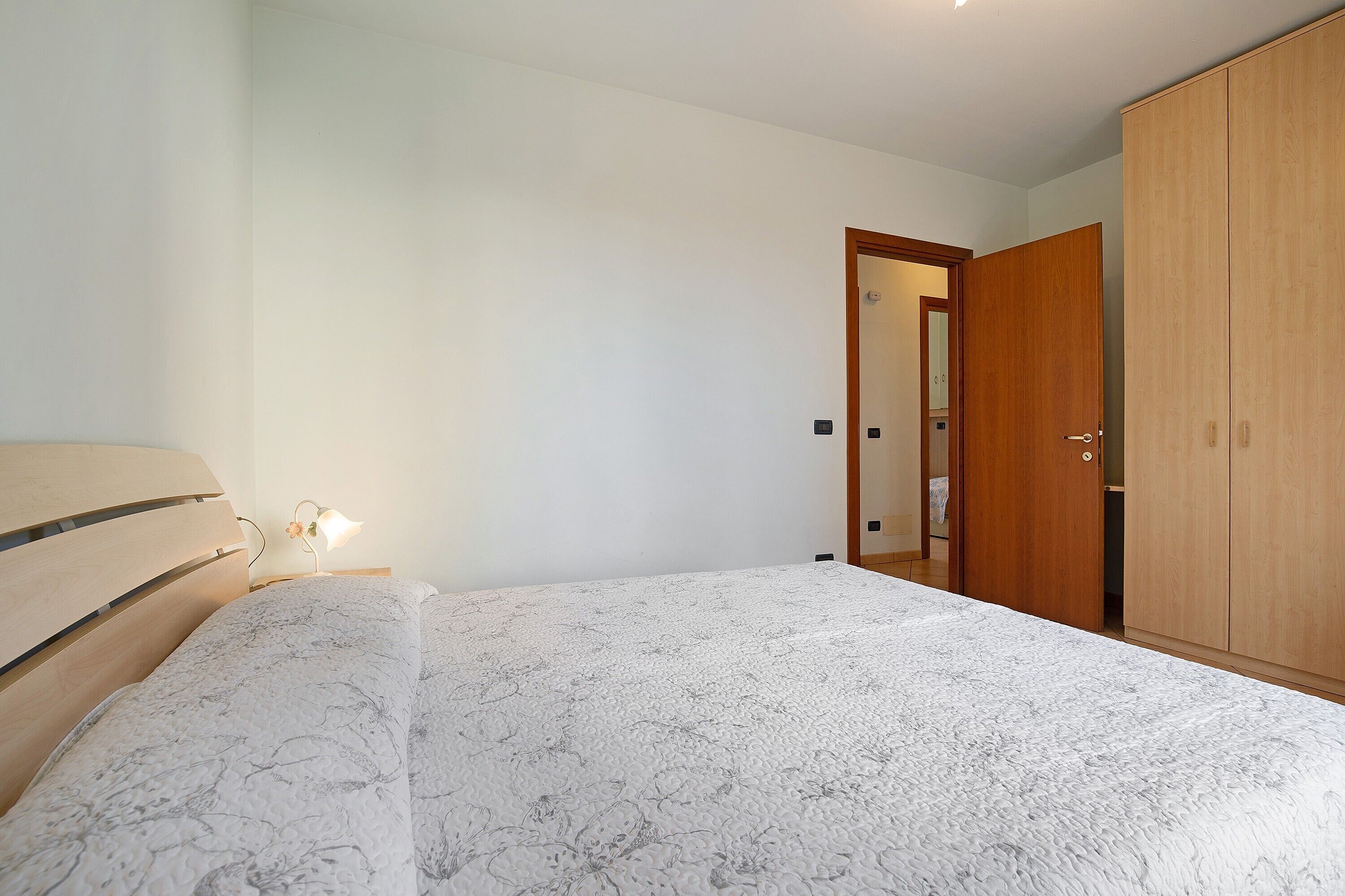 Une chambre à coucher avec un lit, une armoire en bois et une table de chevet avec une lampe.