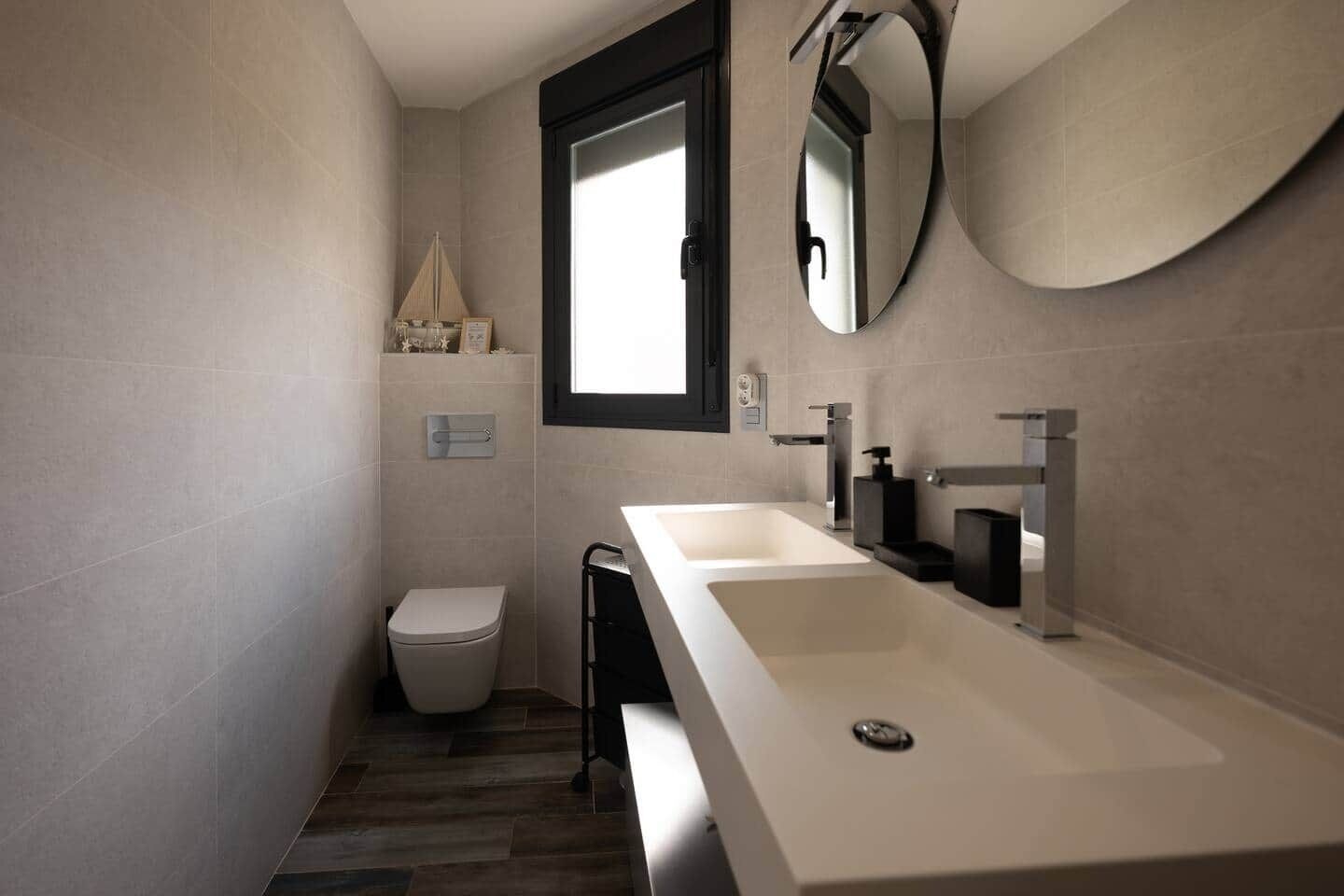 A modern bathroom with a large sink, a toilet, and a mirror.