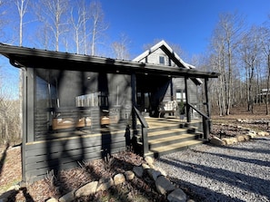 A cabin with a porch, a staircase, and a view of a forest. - New Mountain Tiny Retreat with Beautiful Deck in Tennessee (Monteagle)