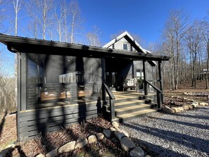 A cabin with a porch, a staircase, and a view of a forest. - New Mountain Tiny Retreat with Beautiful Deck in Tennessee (Monteagle)