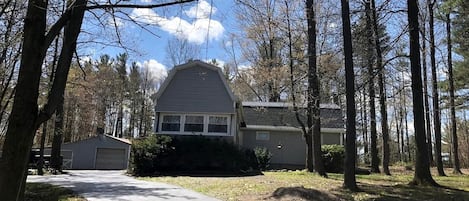 A residential house with a driveway, surrounded by trees.