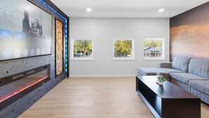 Een moderne woonkamer met een open haard, een bank, een bijzettafeltje en ingelijste foto's aan de muur.