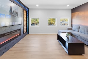 A modern living room with a fireplace, a sofa, a coffee table, and framed pictures on the wall. - Modern home near Convention Center (Indianapolis)