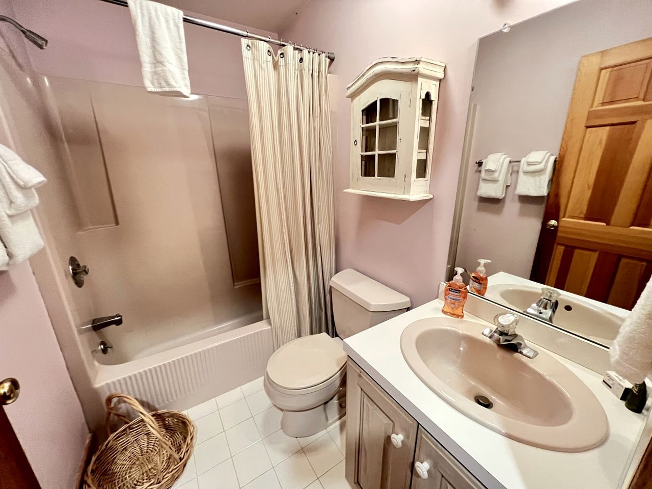 A bathroom with a bathtub, toilet, shower curtain, and a sink with a mirror.