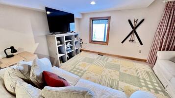 A bedroom with a bed, a TV, a window, and a wall-mounted decoration.