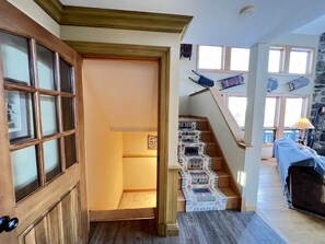 Un escalier recouvert d’une moquette à motifs, une porte en bois avec des panneaux de verre et un mur en pierre.