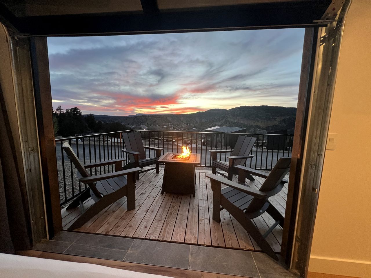 A deck with a fire pit and chairs, overlooking a scenic landscape.