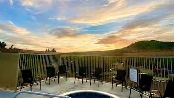Un bain à remous avec une piscine, entouré de chaises, et offrant une vue sur le ciel et le paysage.