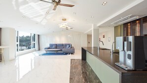 A modern kitchen with a built-in refrigerator, a dining area with a bar counter, and a seating area with a sofa. - Elren Hotel (Seogwipo)