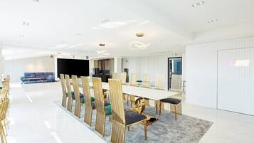 A modern conference room with a long table, golden chairs, and a large screen.