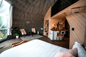 Un hébergement sous tente comprenant un lit, un coin salon et une kitchenette.