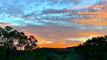 A sunset over a forested landscape with trees silhouetted against the sky.