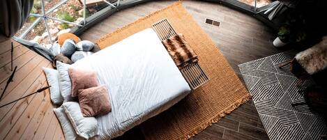 A circular room with a bed, a woven rug, and a geometric rug.
