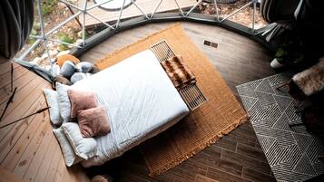 Une pièce circulaire comprenant un lit, un tapis tissé et un tapis à motifs géométriques.