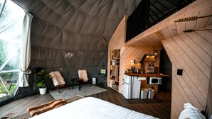 Alojamiento tipo tienda con cama, zona de estar y kitchenette.