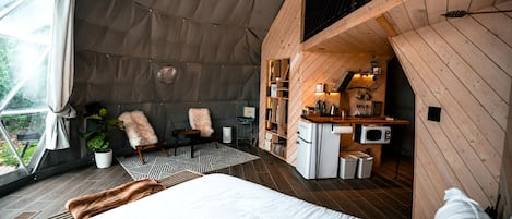 Alojamiento tipo tienda con cama, zona de estar y kitchenette.