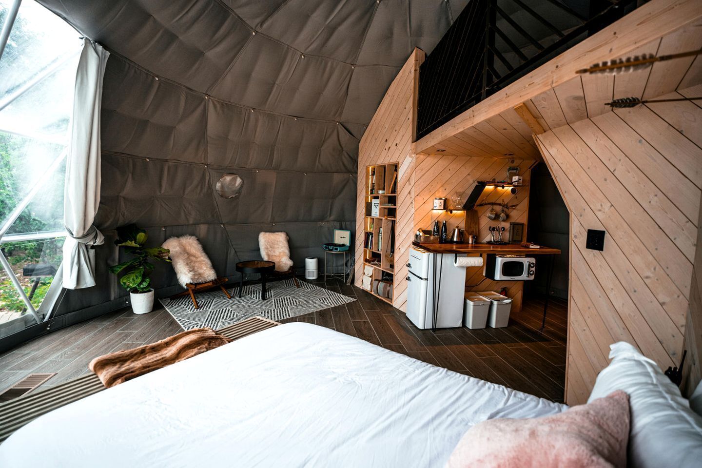 A tented accommodation with a bed, seating area, and kitchenette.