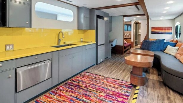 Een compacte keuken met moderne apparatuur, een kleurrijk vloerkleed en een gezellige zithoek met een ronde houten tafel.