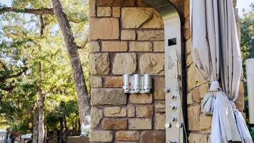 A stone-built outdoor structure with a metal grill, a hanging umbrella, and a small seating area.