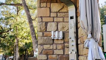 A stone-built outdoor shower with a metal showerhead and a towel hanging on the side.