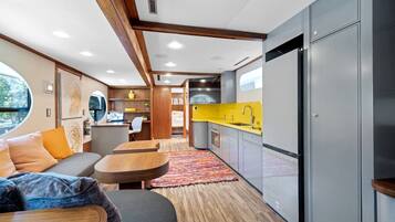 A compact living space with a kitchenette, seating area, and a view through a window.