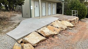 A building with a covered entrance, a concrete ramp, and a stone wall. - Wilderness Cabin Rental Perfect for Glamping in Texas (Graford)