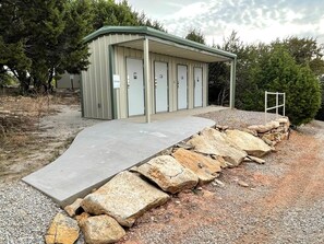 A building with a covered entrance, a concrete ramp, and a stone wall. - Wilderness Cabin Rental Perfect for Glamping in Texas (Graford)