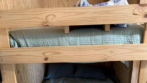 A bunk bed with a blue mattress and a wooden frame. - Wilderness Cabin Rental Perfect for Glamping in Texas (Graford)