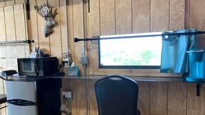 A kitchen with a microwave, refrigerator, and a window with a view. - Wilderness Cabin Rental Perfect for Glamping in Texas (Graford)