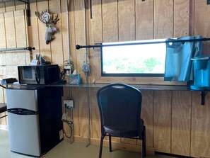 A kitchen with a microwave, refrigerator, and a window with a view. - Wilderness Cabin Rental Perfect for Glamping in Texas (Graford)