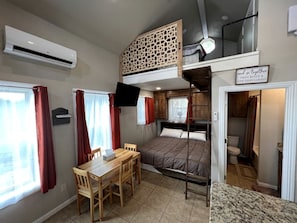 A compact room with bunk beds, a desk, and a small table.