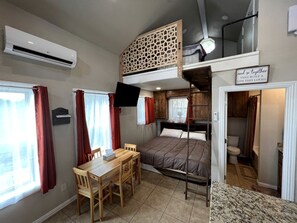 A compact room with bunk beds, a desk, and a small table.