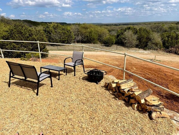 Un espacio al aire libre con una chimenea, una silla y una mesa.