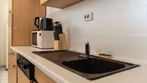 A kitchen with a black sink, a coffee maker, and a microwave. - 2BR Apartment Long Stay Up to 6 Guests (Vienna)
