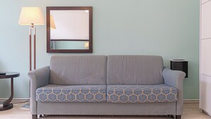 A grey sofa with a patterned cushion, a floor lamp, and a mirror on the wall. - 2BR Apartment Long Stay Up to 6 Guests (Vienna)