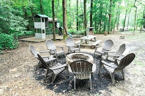 A campsite with a fire pit, picnic table, and Adirondack chairs arranged around it. - Tiny Home Cottage Near the Smokies #4 Stella, Sevierville, Tennessee (Sevierville)